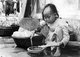 Vietnam: Young girl grilling rice paper, Hoi An (1940)